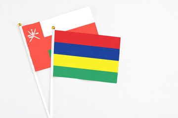 Mauritius and Oman stick flags on white background. High quality fabric, miniature national flag. Peaceful global concept.White floor for copy space.