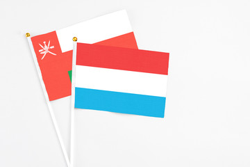 Luxembourg and Oman stick flags on white background. High quality fabric, miniature national flag. Peaceful global concept.White floor for copy space.