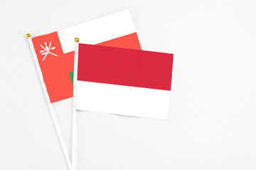 Monaco and Oman stick flags on white background. High quality fabric, miniature national flag. Peaceful global concept.White floor for copy space.