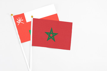 Morocco and Oman stick flags on white background. High quality fabric, miniature national flag. Peaceful global concept.White floor for copy space.