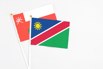 Namibia and Oman stick flags on white background. High quality fabric, miniature national flag. Peaceful global concept.White floor for copy space.