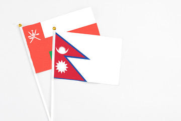 Nepal and Oman stick flags on white background. High quality fabric, miniature national flag. Peaceful global concept.White floor for copy space.