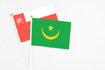 Mauritania and Oman stick flags on white background. High quality fabric, miniature national flag. Peaceful global concept.White floor for copy space.