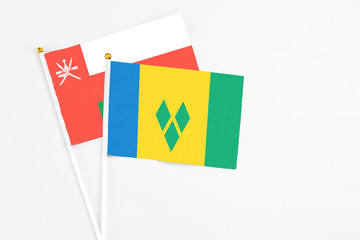 Saint Vincent And The Grenadines and Oman stick flags on white background. High quality fabric, miniature national flag. Peaceful global concept.White floor for copy space.