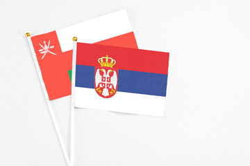 Serbia and Oman stick flags on white background. High quality fabric, miniature national flag. Peaceful global concept.White floor for copy space.