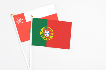 Portugal and Oman stick flags on white background. High quality fabric, miniature national flag. Peaceful global concept.White floor for copy space.