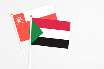 Sudan and Oman stick flags on white background. High quality fabric, miniature national flag. Peaceful global concept.White floor for copy space.