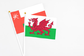 Wales and Oman stick flags on white background. High quality fabric, miniature national flag. Peaceful global concept.White floor for copy space.