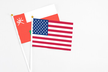 United States and Oman stick flags on white background. High quality fabric, miniature national flag. Peaceful global concept.White floor for copy space.