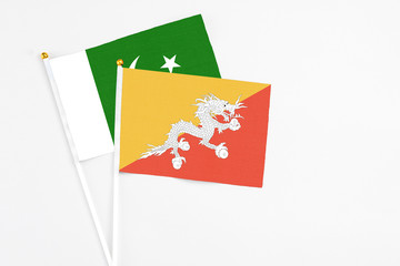 Bhutan and Pakistan stick flags on white background. High quality fabric, miniature national flag. Peaceful global concept.White floor for copy space.