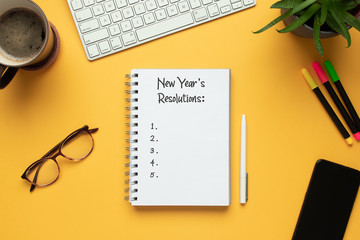 Stock photo of 2020 new year notebook with list of resolutions and objects on yellow background