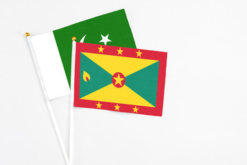 Grenada and Pakistan stick flags on white background. High quality fabric, miniature national flag. Peaceful global concept.White floor for copy space.