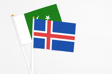 Iceland and Pakistan stick flags on white background. High quality fabric, miniature national flag. Peaceful global concept.White floor for copy space.