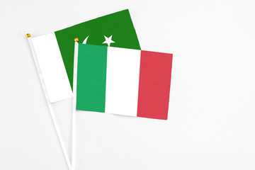 Italy and Pakistan stick flags on white background. High quality fabric, miniature national flag. Peaceful global concept.White floor for copy space.