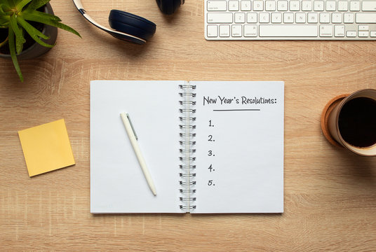 Stock photo of new year notebook with list of resolutions and objects on wooden background