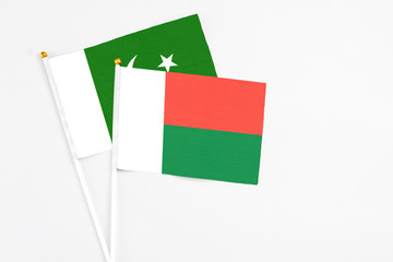 Madagascar and Pakistan stick flags on white background. High quality fabric, miniature national flag. Peaceful global concept.White floor for copy space.