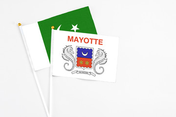 Mayotte and Pakistan stick flags on white background. High quality fabric, miniature national flag. Peaceful global concept.White floor for copy space.