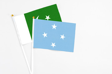 Micronesia and Pakistan stick flags on white background. High quality fabric, miniature national flag. Peaceful global concept.White floor for copy space.