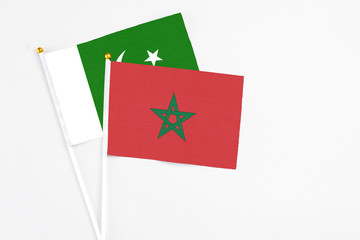 Morocco and Pakistan stick flags on white background. High quality fabric, miniature national flag. Peaceful global concept.White floor for copy space.