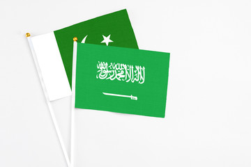Saudi Arabia and Pakistan stick flags on white background. High quality fabric, miniature national flag. Peaceful global concept.White floor for copy space.