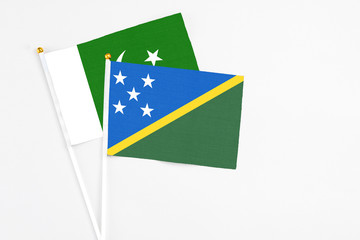 Solomon Islands and Pakistan stick flags on white background. High quality fabric, miniature national flag. Peaceful global concept.White floor for copy space.