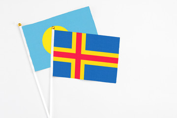 Aland Islands and Palau stick flags on white background. High quality fabric, miniature national flag. Peaceful global concept.White floor for copy space.