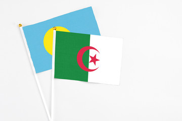 Algeria and Palau stick flags on white background. High quality fabric, miniature national flag. Peaceful global concept.White floor for copy space.