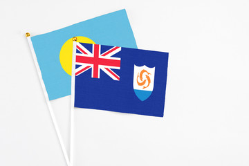 Anguilla and Palau stick flags on white background. High quality fabric, miniature national flag. Peaceful global concept.White floor for copy space.