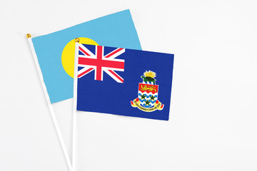 Cayman Islands and Palau stick flags on white background. High quality fabric, miniature national flag. Peaceful global concept.White floor for copy space.