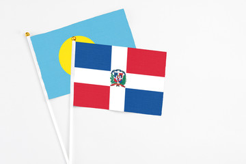 Dominican Republic and Palau stick flags on white background. High quality fabric, miniature national flag. Peaceful global concept.White floor for copy space.