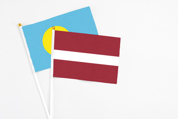 Latvia and Palau stick flags on white background. High quality fabric, miniature national flag. Peaceful global concept.White floor for copy space.