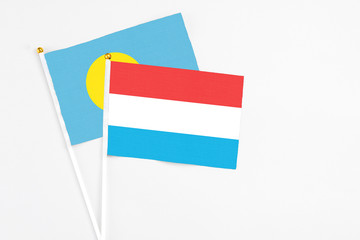 Luxembourg and Palau stick flags on white background. High quality fabric, miniature national flag. Peaceful global concept.White floor for copy space.