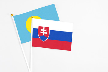 Slovakia and Palau stick flags on white background. High quality fabric, miniature national flag. Peaceful global concept.White floor for copy space.