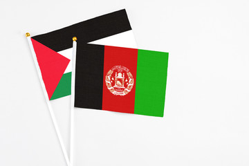 Afghanistan and Palestine stick flags on white background. High quality fabric, miniature national flag. Peaceful global concept.White floor for copy space.