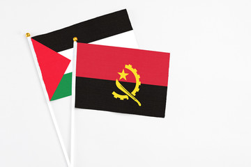 Angola and Palestine stick flags on white background. High quality fabric, miniature national flag. Peaceful global concept.White floor for copy space.