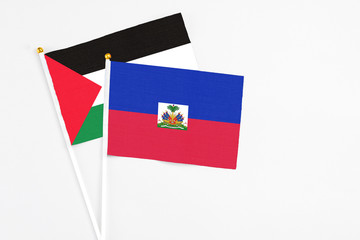 Haiti and Palestine stick flags on white background. High quality fabric, miniature national flag. Peaceful global concept.White floor for copy space.