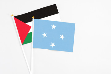 Micronesia and Palestine stick flags on white background. High quality fabric, miniature national flag. Peaceful global concept.White floor for copy space.
