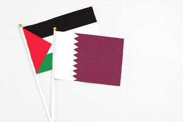 Qatar and Palestine stick flags on white background. High quality fabric, miniature national flag. Peaceful global concept.White floor for copy space.