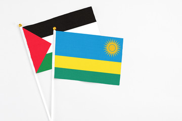 Rwanda and Palestine stick flags on white background. High quality fabric, miniature national flag. Peaceful global concept.White floor for copy space.