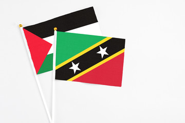 Saint Kitts And Nevis and Palestine stick flags on white background. High quality fabric, miniature national flag. Peaceful global concept.White floor for copy space.