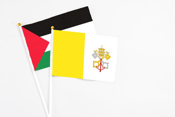 Vatican City and Palestine stick flags on white background. High quality fabric, miniature national flag. Peaceful global concept.White floor for copy space.