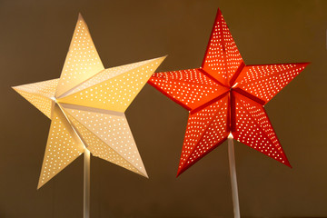 Lamps in the form of a star with holes on a pole of yellow red color on a background of brown...