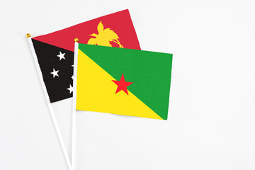 French Guiana and Papua New Guinea stick flags on white background. High quality fabric, miniature national flag. Peaceful global concept.White floor for copy space.
