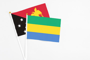 Gabon and Papua New Guinea stick flags on white background. High quality fabric, miniature national...