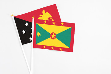 Grenada and Papua New Guinea stick flags on white background. High quality fabric, miniature national flag. Peaceful global concept.White floor for copy space.