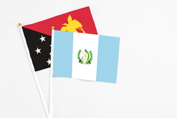 Guatemala and Papua New Guinea stick flags on white background. High quality fabric, miniature national flag. Peaceful global concept.White floor for copy space.