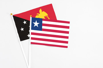 Liberia and Papua New Guinea stick flags on white background. High quality fabric, miniature national flag. Peaceful global concept.White floor for copy space.