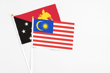 Malaysia and Papua New Guinea stick flags on white background. High quality fabric, miniature national flag. Peaceful global concept.White floor for copy space.