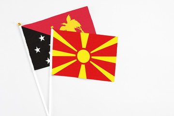 Macedonia and Papua New Guinea stick flags on white background. High quality fabric, miniature national flag. Peaceful global concept.White floor for copy space.