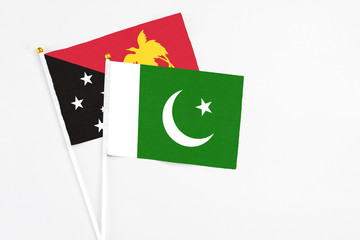 Pakistan and Papua New Guinea stick flags on white background. High quality fabric, miniature national flag. Peaceful global concept.White floor for copy space.